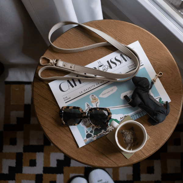 cream leash on table with tea and sunglasses