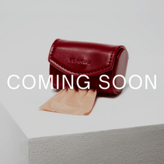 Red leather case with a beige fabric on a gray surface, labeled 'Coming Soon'.